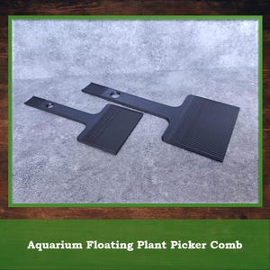 May include: Two black aquarium floating plant picker combs. Each comb has a rectangular head with parallel grooves and a handle with a hole. The combs are designed for removing floating plants from aquariums.
