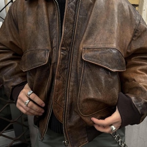 Blouson aviateur en cuir marron vieilli vintage des années 90, style aviateur classique, veste robuste pour hommes avec poches aux poignets côtelés en cuir de mouton
