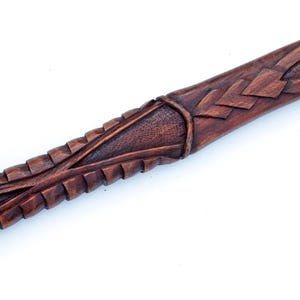 Puede incluir: Primer plano de un bast&oacute;n de madera con tallas intrincadas. El bast&oacute;n es de color marr&oacute;n oscuro y tiene un acabado liso y pulido.