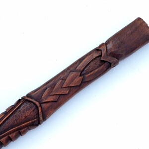 Puede incluir: Primer plano de un bast&oacute;n de madera con tallas intrincadas. El bast&oacute;n es de color marr&oacute;n oscuro y tiene un acabado liso y pulido.