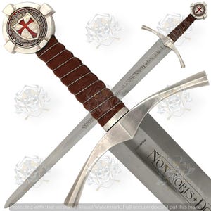 May include: A medieval-style sword with a silver blade and guard, and a brown leather-wrapped handle. The hilt features a circular emblem with a red cross. The blade has the inscription "NON NOBIS DOMINE NON NOBIS SED GLORIAE".