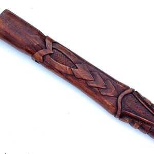 Puede incluir: Primer plano de una vaina de madera con intrincados tallados. La vaina es de color marr&oacute;n oscuro y tiene un dise&ntilde;o de nudo celta.