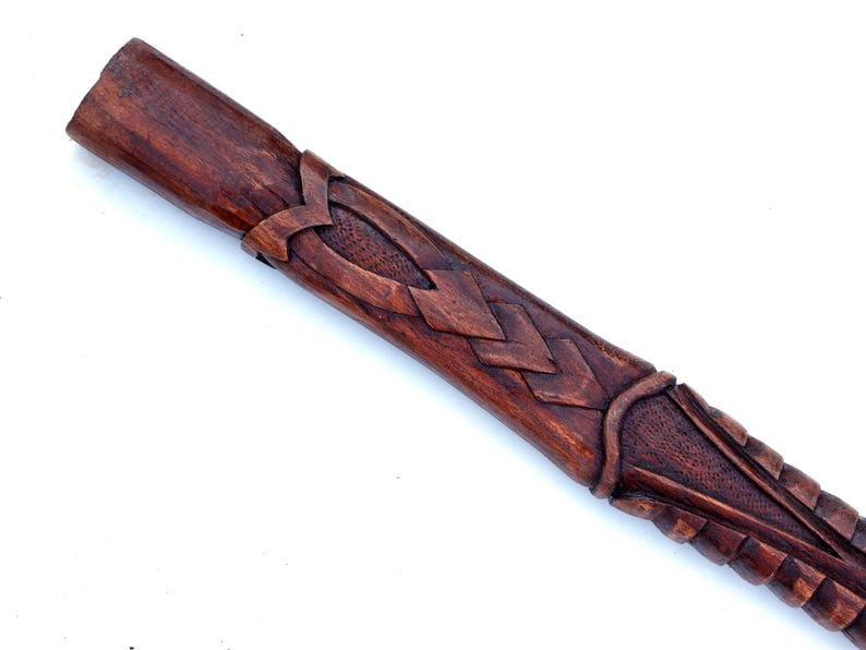 Puede incluir: Primer plano de una vaina de madera con intrincados tallados. La vaina es de color marr&oacute;n oscuro y tiene un dise&ntilde;o de nudo celta.