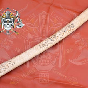 Könnte beinhalten: Ein Holz-Axt-Stiel mit aufwendigen Schnitzereien. Der Stiel ist hellbraun und hat eine glatte Oberfläche. Die Schnitzereien sind dunkelbraun und zeigen ein keltisches Knotenmuster.