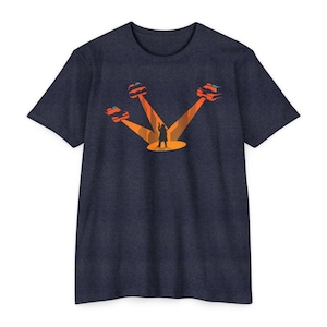 May include: Navy blue t-shirt with a graphic of a person on a stage, illuminated by orange spotlights, with three stylized cars. The cars are red and orange, and the person is a silhouette.