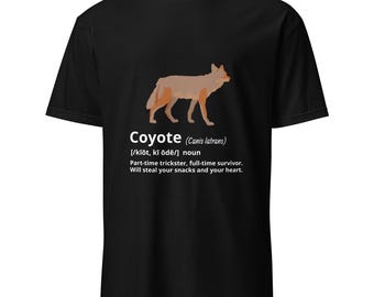 May include: Black t-shirt featuring an illustration of a coyote and the definition of the word "coyote" in white text. The definition includes the scientific name, pronunciation, and a description of the animal.