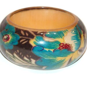Pode incluir: Um bracelete de madeira com um design floral. O bracelete é castanho com flores azuis, amarelas e vermelhas.