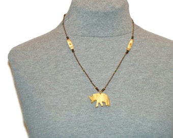 May include: A wooden elephant pendant necklace with brown and green beads. The pendant is carved in the shape of an elephant and is a light brown color.