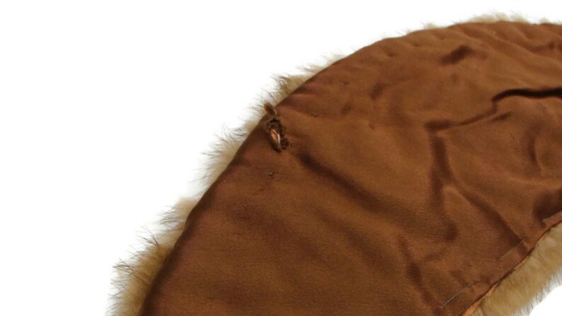 K&ouml;nnte beinhalten: Ein brauner Pelzkragen mit braunem Satin-Futter. Der Kragen hat eine kleine Schlaufe auf der R&uuml;ckseite.