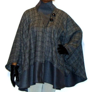 Pode incluir: Um poncho com padrão cinza e preto com forro azul e dois botões pretos. O poncho tem um caimento solto e um design fluido.