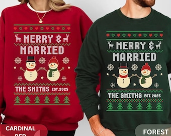 Könnte beinhalten: Zwei Sweatshirts, eines in Kardinalrot und eines in Waldgrün, zeigen ein festliches Design. Das Design beinhaltet den Text "MERRY & MARRIED", Schneemänner, Schneeflocken und den Namen "THE SMITHS EST. 2025".