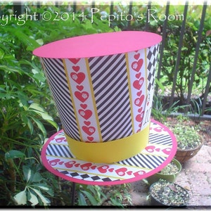 May include: A red, black, and white top hat with a yellow band and a heart and diamond pattern. The hat is made of paper and is decorated with a red heart and diamond pattern.