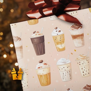 May include: Gift wrap featuring a repeating pattern of illustrated iced coffee drinks in various styles. The drinks are in clear plastic cups with whipped cream, coffee beans, and straws. The background is a light pink color.