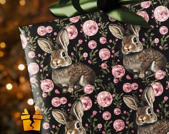 May include: Gift wrapping paper featuring a repeating pattern of brown rabbits, pink floral orbs, and green foliage on a black background. A dark green bow sits atop the wrapped gift. The overall theme is Easter or spring.