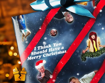 May include: A wrapped gift with a blue bow and red ribbon. The wrapping paper has a blue background with snowflakes and images of people. The text "I Think You Should Have a Merry Christmas" is printed on the front.