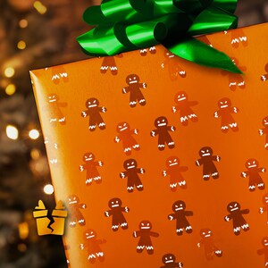 May include: A wrapped gift with orange wrapping paper featuring a pattern of gingerbread men. The gift is topped with a large green bow. The background is blurred with warm-toned lights, suggesting a festive holiday theme.