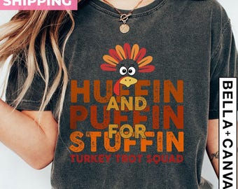 May include: Dark gray t-shirt with a turkey graphic and the text "Huffin and Puffin for Stuffin". The shirt also has the text "Turkey Trot Squad". The shirt is made of a soft, comfortable material.