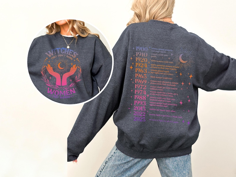 May include: A dark gray sweatshirt with a graphic print on the front that says "Witches, they don't burn, they rise" with a crescent moon and two hands holding a star. The back of the sweatshirt has a list of years and events related to women's rights.