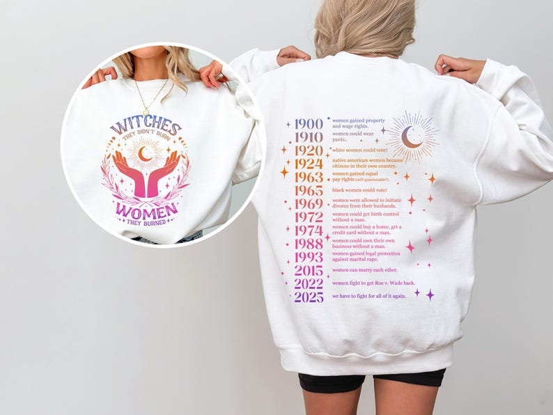 May include: White sweatshirt with a pink and purple graphic of hands holding a crescent moon and stars with the text "Witches they don't burn women they shine" on the front. The back of the sweatshirt has a list of historical events related to women's rights in the United States.