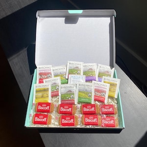 May include: A gift box containing Birchall tea bags and Biscoff biscuits. The tea selection includes various flavours, and the biscuits are in red packaging. The box is open, revealing the contents arranged neatly inside.