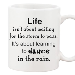 May include: White ceramic coffee mug with black text that reads "Life isn't about waiting for the storm to pass. It's about learning to dance in the rain."