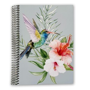 May include: A spiral-bound notebook with a light gray cover featuring a watercolor illustration of a hummingbird in flight, surrounded by green palm leaves and two large hibiscus flowers in shades of pink, orange, and white.