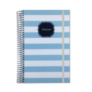 May include: A spiral-bound planner featuring a light blue and white horizontal striped pattern. The cover includes a centered dark navy blue scalloped label with the word Planner printed in white text. A thin vertical elastic band secures the cover.