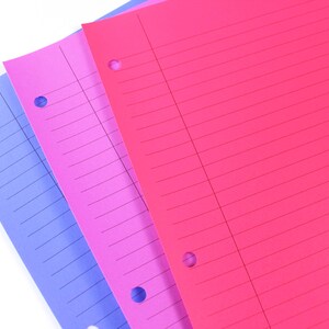 May include: Three sheets of lined paper in shades of blue, pink, and red. Each sheet has three holes for binder use. The paper is arranged diagonally, with the colours overlapping.