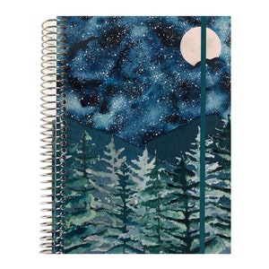 May include: A blue spiral bound notebook with a watercolor design of a starry night sky, a full moon, and a forest of pine trees. The notebook has a teal ribbon bookmark.