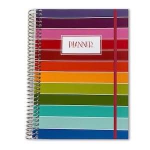 May include: A spiral-bound planner featuring a horizontal striped pattern in a rainbow of colors including purple, pink, red, orange, yellow, green, teal, and blue. A white rectangular label in the center displays the word PLANNER in red text.