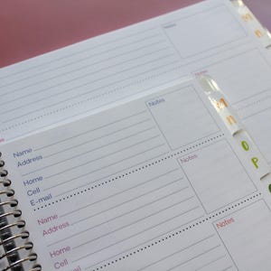 a spiral-bound notebook with a page for contact information and a separate page for notes. The notebook appears to be organized and ready for use.