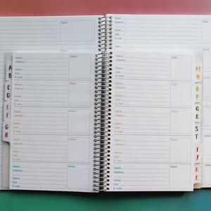 an open spiral-bound notebook with multiple pages, each containing a form for recording contact information. The notebook has a colorful and organized layout, with each page divided into sections for different types of information, such as names, addresses, and phone numbers. The overall appearance of the notebook suggests it is designed for use in a professional or personal context, where the ability to organize and retrieve contact information is essential.