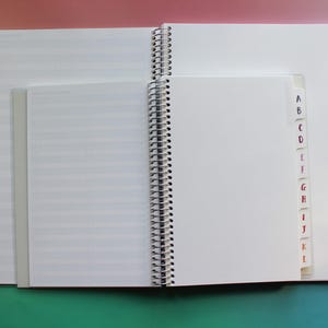 an open spiral-bound notebook with blank pages, placed on a colorful background.