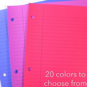 May include: Three colourful, lined notebooks in shades of blue, pink, and red. Each notebook has a three-hole punch and horizontal lines. Text at the bottom reads "20 colours to choose from."