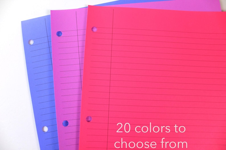 May include: Three colourful, lined notebooks in shades of blue, pink, and red. Each notebook has a three-hole punch and horizontal lines. Text at the bottom reads "20 colours to choose from."