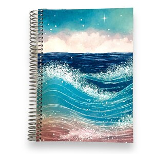 May include: A blue and green spiral bound notebook with a watercolor design of ocean waves crashing on a beach. The cover features a light blue sky with white clouds and a single star.