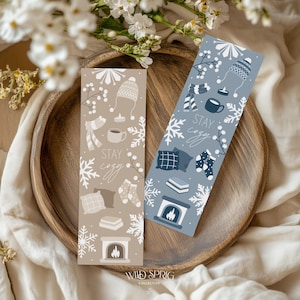 May include: Two bookmark designs with a winter theme. One bookmark is brown with white snowflakes and the text "Stay Cozy". The other bookmark is blue with white snowflakes and the text "Stay Cozy".