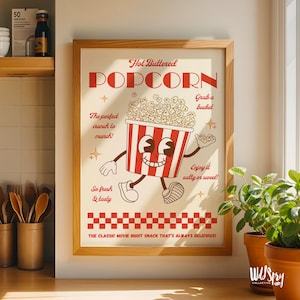 Puede incluir: Un póster enmarcado de estilo vintage con una ilustración de cubo de palomitas de dibujos animados. El cubo a rayas rojas y blancas está sonriendo y sosteniendo palomitas de maíz. El texto incluye "Hot Buttered POPCORN" y "The classic movie night snack that's always delicious!"