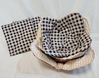 May include: Set of three quilted bowl cozies in black and white gingham with orange accents. The cozies are made of fabric and are designed to protect bowls from heat.