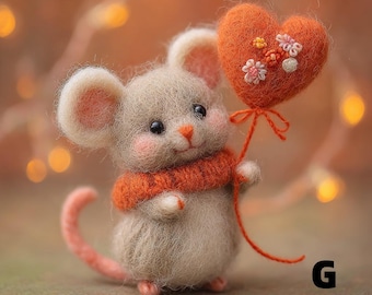 Puede incluir: Una figura de ratón de fieltro hecha a mano con un cuerpo gris claro, orejas rosas y una cola a juego. Lleva una bufanda naranja y sostiene un globo en forma de corazón naranja decorado con pequeñas flores. La letra "G" está en la esquina inferior derecha.