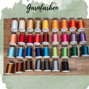 Puede incluir: Una colecci&oacute;n de coloridas bobinas de hilo, cada una etiquetada con un n&uacute;mero &uacute;nico. La imagen presenta una variedad de tonos, incluyendo blanco, dorado, amarillo, naranja, rojo, rosa, azul, verde y marr&oacute;n. La palabra "Garnfarben" est&aacute; escrita en la parte superior.