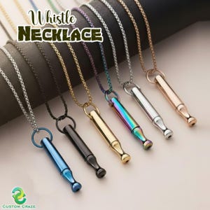 May include: A collection of whistle necklaces in various colors, including blue, black, gold, and iridescent. Each necklace features a chain and a whistle pendant. The image includes the text "Whistle Necklace" at the top.