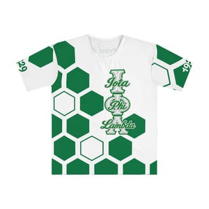 May include: A white short-sleeve t-shirt featuring a green honeycomb pattern on the left side and sleeves. The text Iota Phi Lambda is printed vertically in green and silver on the right side. The number 1929 is visible on the left sleeve.