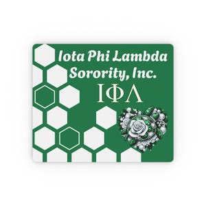 Op de afbeelding: Een groen rechthoekig item met een wit honingraatpatroon aan de linkerkant. De tekst "Iota Phi Lambda Sorority, Inc. IΦΛ" wordt in het wit weergegeven. Een hartvormig ontwerp met een schildpad, witte roos en parels staat rechts.
