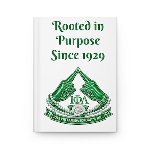 Puede incluir: Un diario blanco con el texto "Rooted in Purpose Since 1929" en verde. La portada presenta un emblema verde con dos manos enguantadas, un collar de perlas, una rosa blanca y el texto "IOTA PHI LAMBDA SORORITY, INC." en verde.
