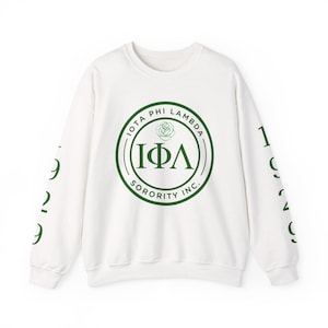 May include: White crew neck sweatshirt with green text and graphics. The front features a circular design with the words "IOTA PHI LAMBDA SORORITY INC." and the Greek letters "ΙΦΛ". The sleeves have the number "1929" printed in green.