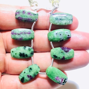 May include: A strand of green and purple gemstone beads, with a rectangular shape, strung on silver wire.