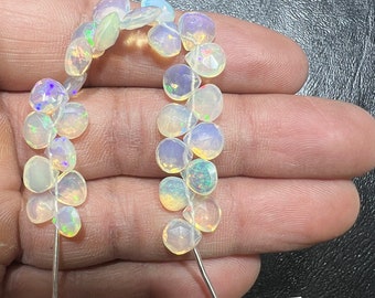 May include: A strand of 18 natural Australian opal beads. The beads are faceted and have a white, iridescent color. The beads are strung on a silver wire and are approximately 6.5 mm in size.