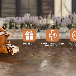 A charming plush fox and two articulated fox figurines are displayed with a realistic tree trunk container on a rustic wooden table. The background features a blurred garden scene with blooming lavender flowers. Three orange icons highlight features: "Ideal Gift," "Articulated Joint Mechanism," and "Perfect for All Ages."