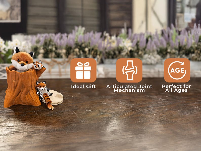 A charming plush fox and two articulated fox figurines are displayed with a realistic tree trunk container on a rustic wooden table. The background features a blurred garden scene with blooming lavender flowers. Three orange icons highlight features: "Ideal Gift," "Articulated Joint Mechanism," and "Perfect for All Ages."